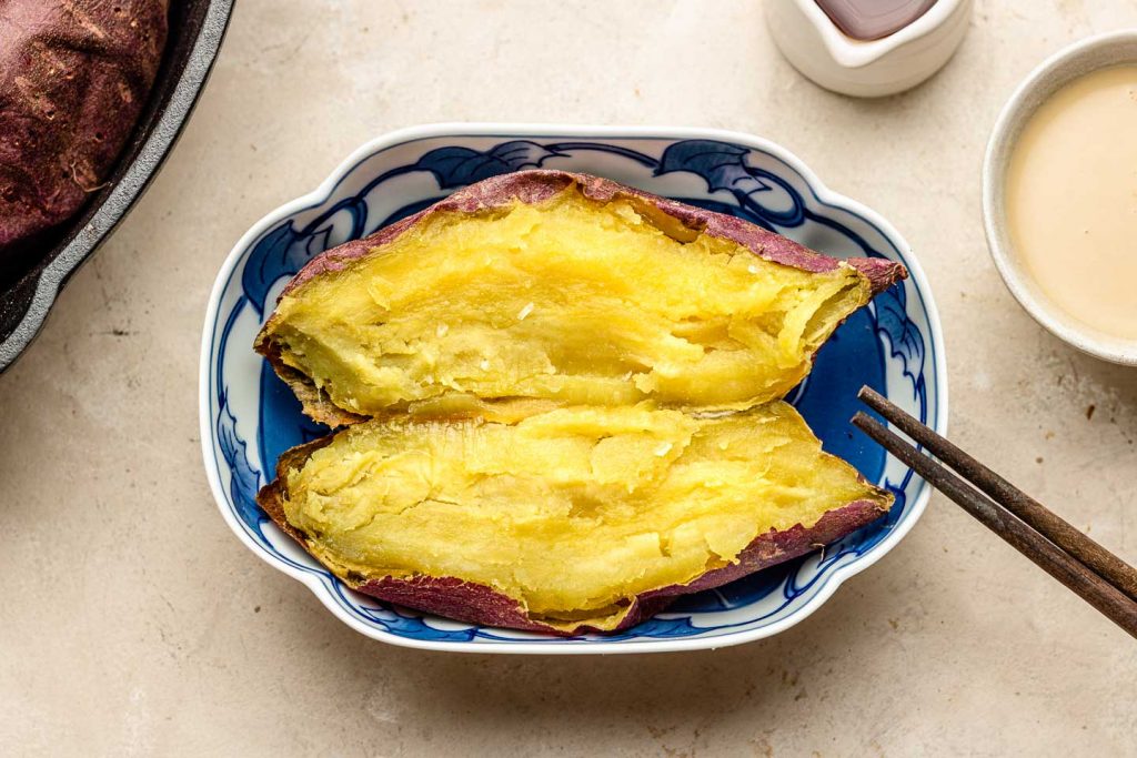  "Baked Japanese sweet potatoes, also known as Yaki Imo, with a crispy and caramelized red-purple skin, and a creamy, sweet, and fluffy texture. A popular and nutritious snack, perfect for fall and winter with chopsticks 