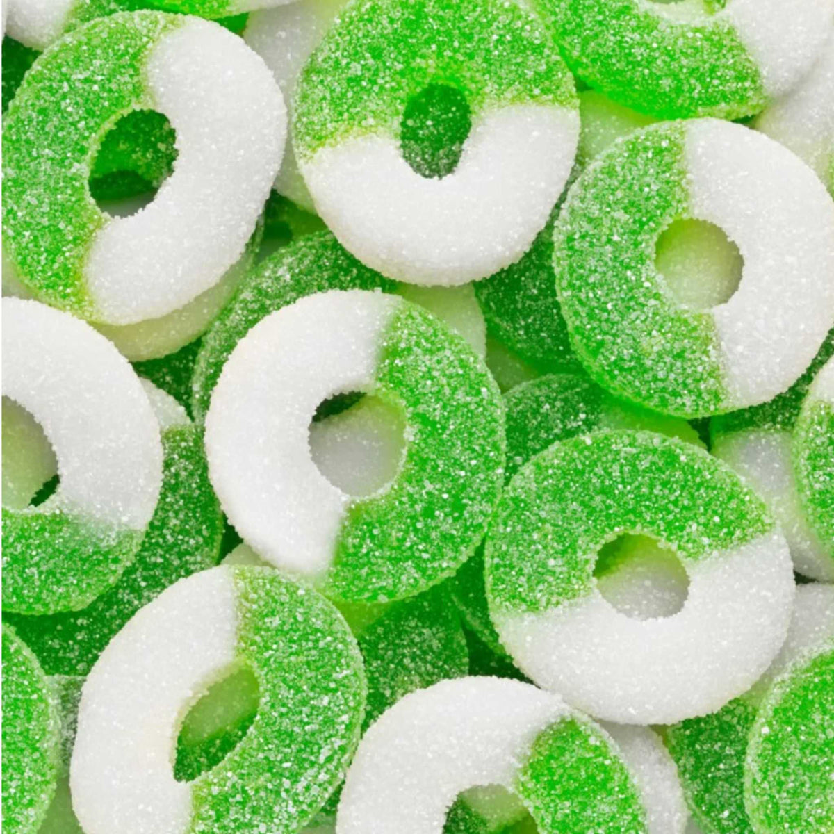 Close-up of sugar-coated green apple gummy rings, half white and half green, with a chewy texture and sour-sweet flavor